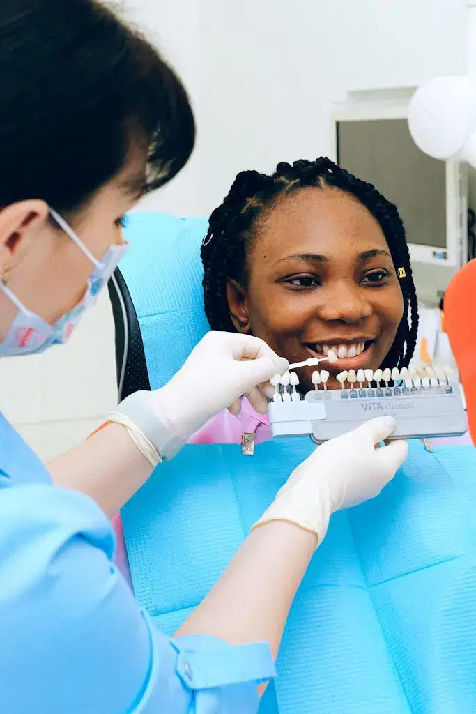 A dentist assists a smiling woman in selecting dental veneers during a check-up.